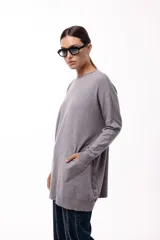 Sweater de silueta amplia y largo medio, con cuello redondo, mangas largas y detalle de botones decorativos en los laterales. Presenta un diseño de tejido de punto con caída relajada.