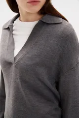 Sweater de punto color azul, con cuello polo y escote en V, de manga larga y diseño holgado.