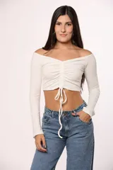 Top de algodón color marrón, con escote off-shoulder, mangas largas y detalle de frunce central con lazo ajustable.