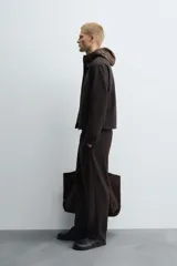 Pantalón regular fit color marrón oscuro, confeccionado en tejido con viscosa. Cuenta con cintura elástica, bolsillos delanteros y detalle de bolsillos traseros de vivo. El cierre frontal es con cremallera y botón.
