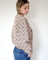 Bomber de diseño amplio en color beige con estampado monograma en marrón, cuello alto y cierre frontal completo.