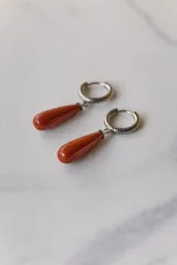 Aros colgantes de acero quirúrgico plateado con dije de piedra natural rosa en forma de lágrima.