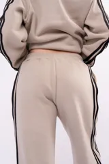 Pantalón deportivo tipo jogger de corte relajado, color negro con franjas laterales blancas y cintura elástica fruncida.