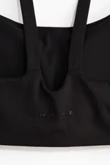 Top deportivo negro con escote redondo, doble tirante en los hombros y diseño de sujeción media.