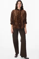 Camisa de manga larga confeccionada en terciopelo con acabado arrugado. Presenta cuello clásico, cierre frontal con botones y puños abotonados.