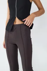 Pantalón de tiro medio color gris oscuro, con corte flare, costura central y pequeña abertura en el ruedo. Cierre frontal oculto.