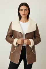 Chaqueta de eco-cuero marrón con textura envejecida, forrada y con detalles de corderito color crema en el cuello, puños y bordes. Presenta un corte holgado y cuello solapa.