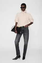 Sweater de tejido acanalado con cuello alto y cierre frontal parcial. Presenta un diseño de corte holgado con mangas largas y puños ajustados.