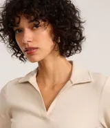 Blusa de manga larga confeccionada en tejido rib de algodón con elastano. Presenta un diseño ajustado al cuerpo con cuello polo y escote en V.