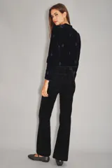 Pantalón de jean con acabado de terciopelo color azul marino, de tiro medio y corte sutilmente acampanado. Presenta cierre y botón frontal, con ruedo ancho como detalle.