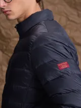 Campera puffer de plumas en color azul marino, con cierre frontal, cuello alto y diseño acolchado horizontal.