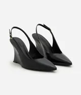 Zapato tipo slingback de color negro con acabado liso. Presenta punta fina, tira trasera ajustable con hebilla metálica y un diseño de taco anabela integrado a la suela.