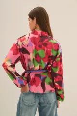 Kimono de corte holgado con estampado floral abstracto en tonos fucsia, rosa, verde y azul. Presenta mangas tres cuartos y diseño abierto frontal.