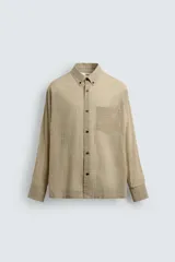 Camisa de hombre de manga larga, color beige con micro-estampado a cuadros en tonos marrones. Presenta cuello solapa abotonado (button-down), un bolsillo de parche en el pecho y cierre frontal de botonadura.