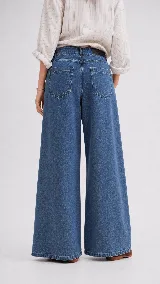 Pantalón de jean color naranja con tiro medio, diseño de pierna ancha y cinco bolsillos. Presenta costuras con pespuntes a contratono.