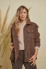 Campera de cuero marrón con efecto desgastado, corte oversize, cuello camisero, cierre frontal con botones y bolsillos frontales con solapa.