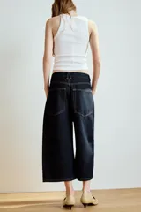 Bermuda baggy de denim azul oscuro con tiro medio, trabillas, cinco bolsillos y costuras en contraste. Cierre frontal con cremallera y botón metálico.