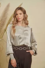 Blusa de satén color champagne con cuello a la base, mangas anchas y puños elásticos con detalle bordado.