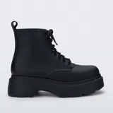 Bota tipo borceguí de la marca Melissa, confeccionada en material sintético mate. Presenta un diseño de caña media con cordones al tono, suela track de plataforma robusta y tirador en la parte trasera.