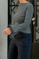 Remera de manga larga con diseño oxford, confeccionada en algodón con estampado de rayas horizontales finas. Presenta un corte ajustado al cuerpo y mangas acampanadas en los puños.