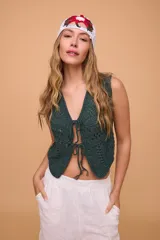 Chaleco corto tejido a mano en crochet, color celeste, con silueta ajustada, sin mangas y lazos en la delantera.