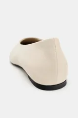 Zapato plano tipo bailarina confeccionado en piel de color beige, con escote redondo y acabado en punta fina.