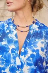 Collar doble de diseño resort, compuesto por cuentas cilíndricas plateadas y tubos texturizados en espiral con detalles de cuentas azules.