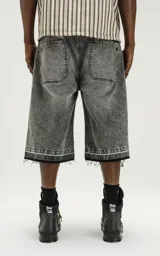Bermuda de denim en color negro con efecto lavado, corte oversize y ruedo desflecado. Incluye un cinturón fino integrado en la cintura.