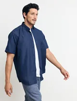 Camisa de manga corta azul con estampado de lunares blancos, cuello abotonado y bolsillo en el pecho.