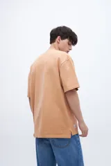 Remera de algodón pesado con calce oversize, cuello redondo con detalle de costura en V y tajos laterales en el ruedo, con un largo posterior ligeramente mayor al delantero.