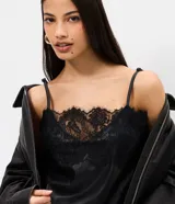 Vestido midi negro de poliuretano, con breteles finos regulables, escote en V y ruedo asimétrico adornados con encaje.