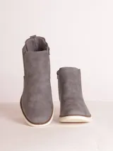 Bota tipo chelsea de cuero sintético color marrón, con paneles laterales elásticos y suela de goma blanca con relieve dentado.