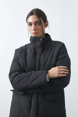 Campera capitoneada de largo medio, color negro, con cuello alto, cierre frontal con cremallera y broches a presión, y bolsillos laterales con solapa.