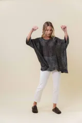 Buzo de tejido liviano con brillo sutil tipo lurex, color beige o dorado claro. Presenta un calce suelto (oversize) con mangas amplias y cuello redondo. El ruedo tiene un detalle de terminación festoneado con pequeños calados.