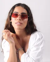 Lentes de sol rectangulares con marco metálico color bronce y cristales rojos.