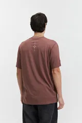 Remera de manga corta color marrón, con ajuste regular y escote redondo. Presenta un estampado frontal con texto en blanco formando un diseño circular.