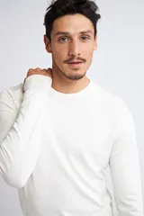 Sweater básico de tejido de punto liviano, color blanco, con cuello redondo, manga larga y logo bordado en el pecho.