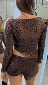 Short de tiro bajo confeccionado en tela transparente con lentejuelas oscuras aplicadas en diseño floral. Presenta un corte ajustado y acabado brillante.