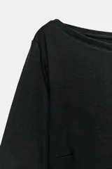 Camiseta de cuello barco y manga larga con diseño asimétrico en el bajo. Presenta un corte entallado con cierre lateral mediante cremallera oculta.