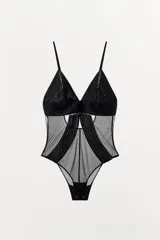 Body negro semitransparente con escote en V y tirantes finos ajustables. Combina paneles de malla con tejido de textura lineal a tono. Posee cierre en la parte inferior con botones a presión y en la espalda con ganchos metálicos.