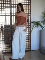 Pantalón wide leg de tiro medio confeccionado en denim, con cintura trabajada con pasacintas entrelazadas, cierre frontal y bolsillos laterales.