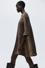 Vestido corto evasé con estampado de leopardo, escote redondo y abertura de cerradura con botón en la nuca. Mangas tres cuartos de corte raglán, pinzas en el busto y bajo recto.