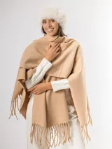 Ruana gris de tejido de punto con flecos en el ruedo.