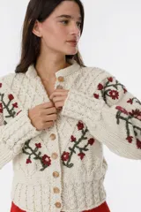 Cárdigan de punto color crema con bordado de flores rojas y verdes.