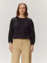 Remera negra de algodón con cuello redondo y mangas largas abullonadas de textura liviana.