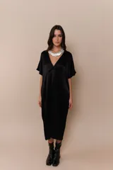 Vestido negro de corte midi, con escote en V y mangas cortas amplias. Presenta un cuello blanco con volados.