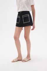 Short de jean color azul oscuro, de calce alto y ajustado al cuerpo. Presenta dos bolsillos frontales cuadrados con bordado decorativo en color blanco.