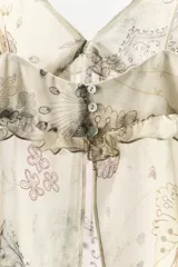 Top lencero de viscosa con estampado sutil, escote en pico y tirantes finos. Presenta detalle de volantes horizontales y lazada frontal en el pecho.