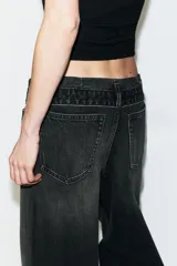 Jeans de mezclilla de tiro medio, corte wide leg y diseño relaxed. Presenta detalles rotos y desgastados en las piernas, y una cinturilla doblada superpuesta con trabillas y cierre frontal con cremallera y botón metálico.
