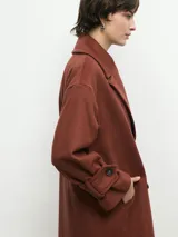 Tapado marrón de paño con doble botonadura, cuello solapa y bolsillos laterales.